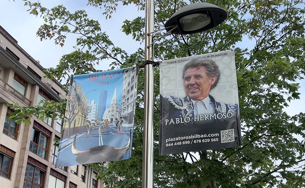 ビルバオ Bilbao 世界的に有名な騎馬闘牛士（レホネアドール）のパブロ・エルモソ・デ・メンドーサのポスターと、近代的なイベルドローラ・タワーが描かれたフラッグ。