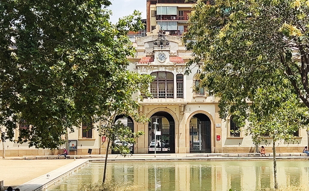 バルセロナ（Barcelona）バイ・グイナルド＝カン・バロ社会サービスセンター（Centre de Serveis Socials Baix Guinardó-Can Baró）静かな水盤を前庭に配した、かつての産業建築を転用したと思われる社会福祉施設の全景