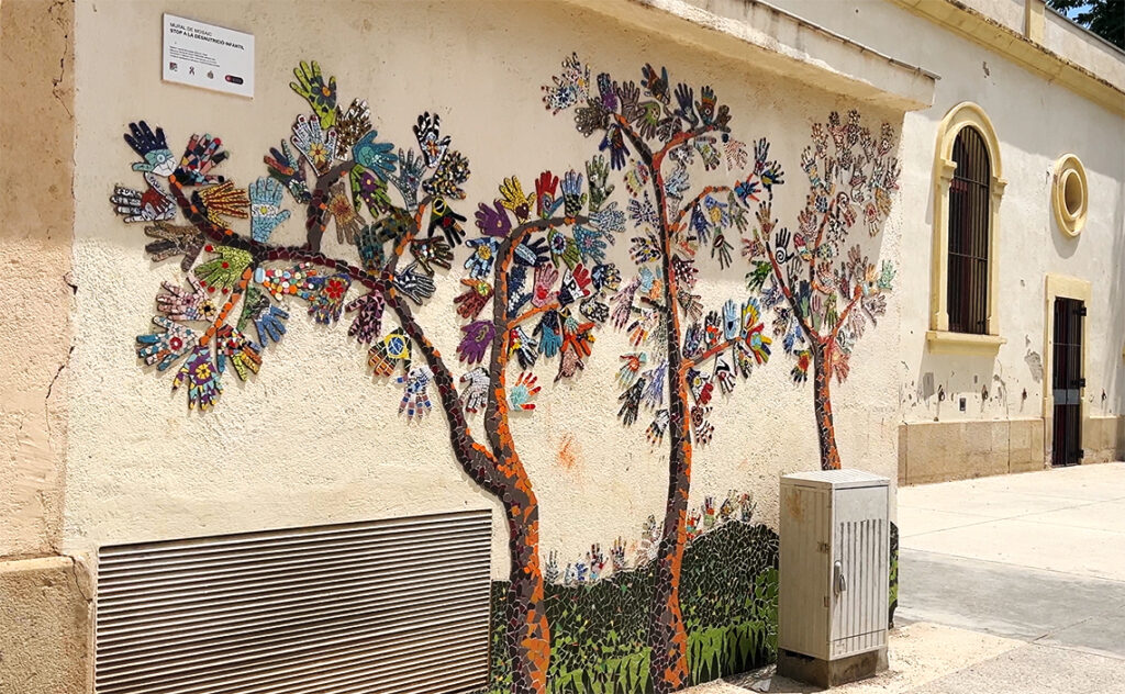 バルセロナ（Barcelona）バイ・グイナルド＝カン・バロ社会サービスセンター（Centre de Serveis Socials Baix Guinardó-Can Baró）施設の白い外壁に施された、色とりどりのセラミック片を用いたトレンカディス（破砕タイル）手法によるモザイク壁画